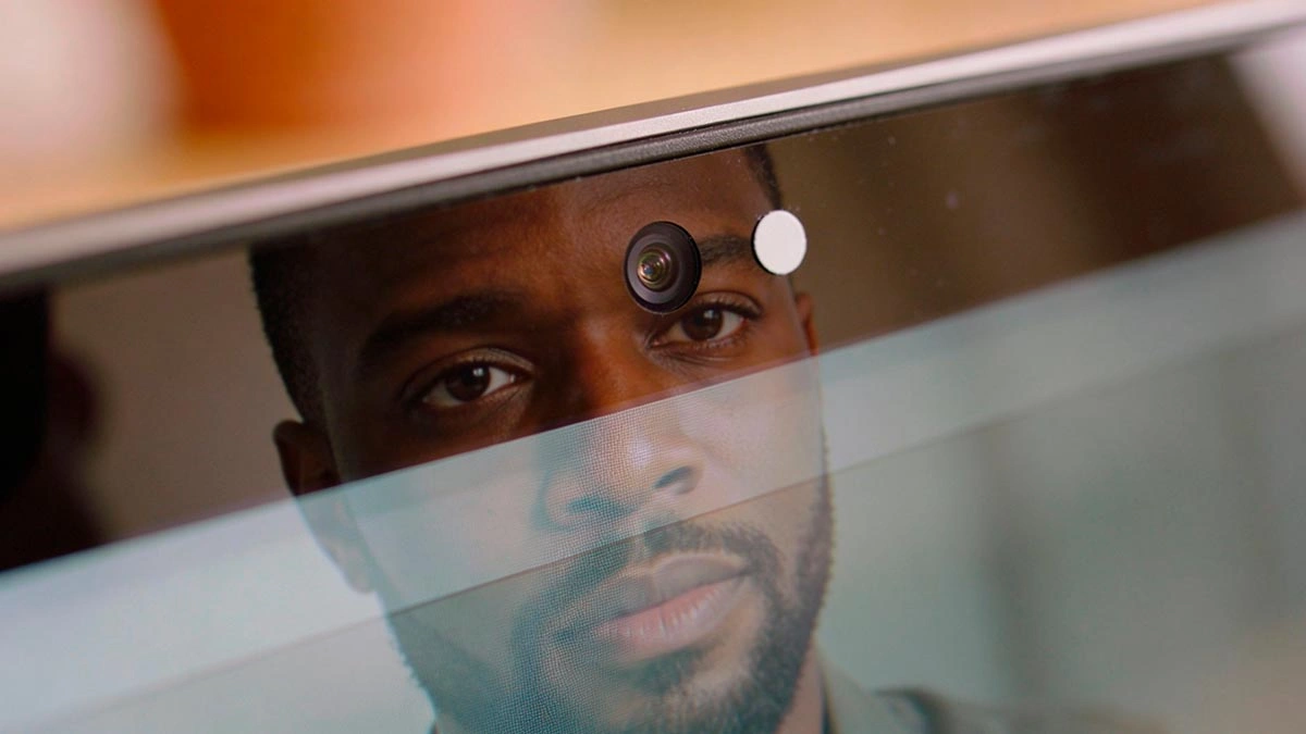 eye contact on webcam: close-up of webcam lens with a tiny matte paper dot cue beside it